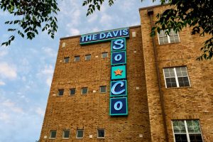 The Davis Soco Urban Industrial Illuminated Neon Wall Identity Sign During the Day